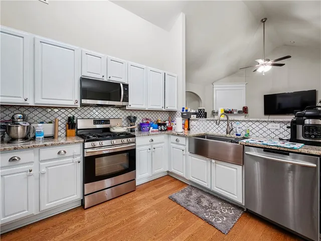 a kitchen with granite countertop a sink a stove a microwave and cabinets