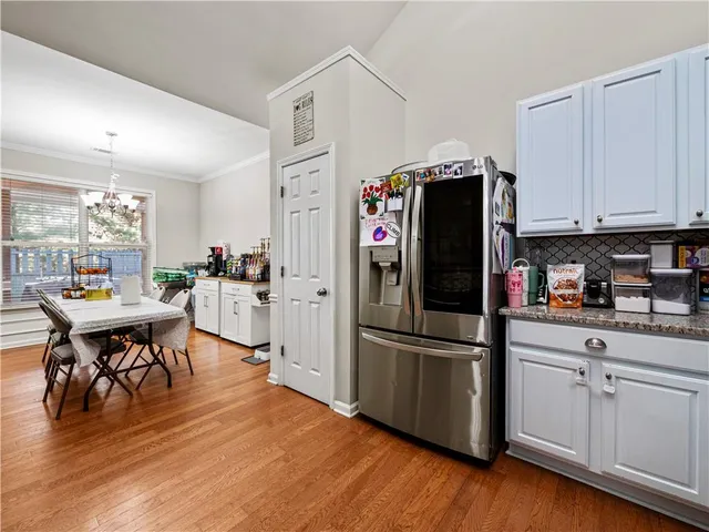 a kitchen with stainless steel appliances a refrigerator a stove a sink dishwasher and white cabinets with wooden floor