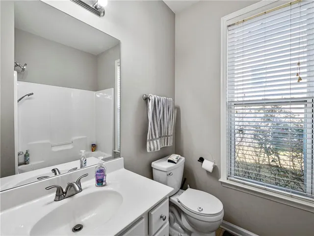 a bathroom with a sink mirror toilet and next to a window