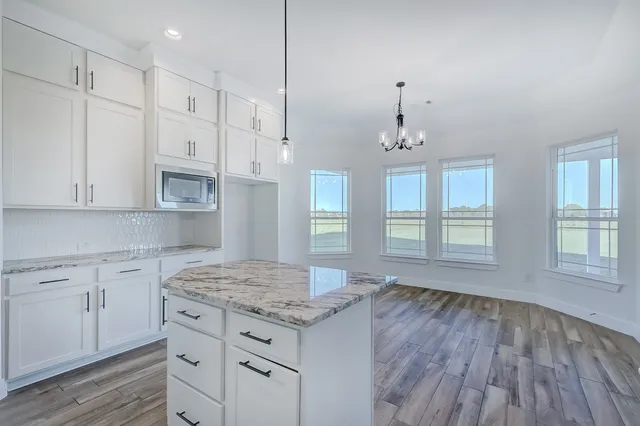 a kitchen with granite countertop white cabinets and a wooden floor