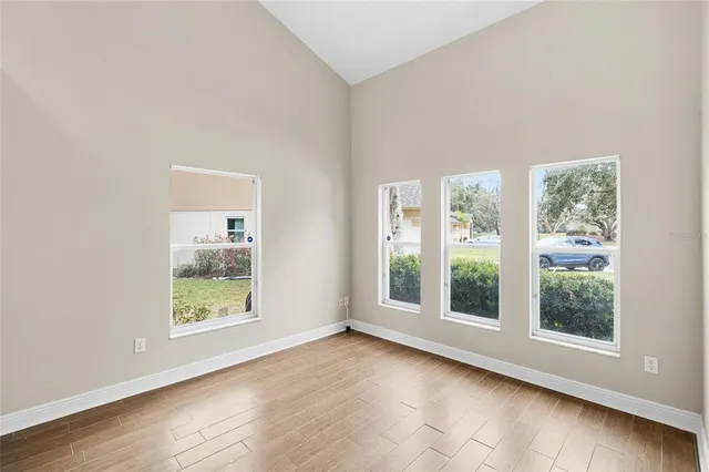 an empty room with wooden floor and windows