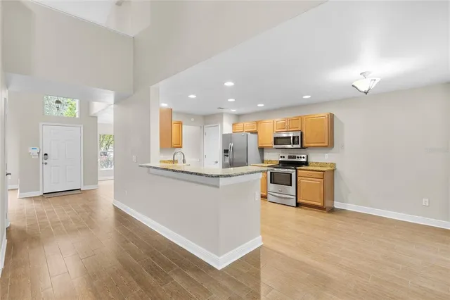 a kitchen with stainless steel appliances kitchen island granite countertop a stove a sink and a refrigerator
