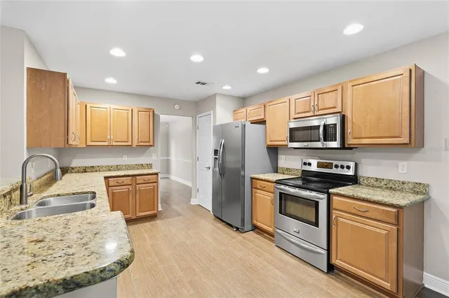 a kitchen with stainless steel appliances granite countertop a sink stove microwave and refrigerator