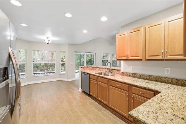 a large kitchen with kitchen island granite countertop a sink a window and stainless steel appliances