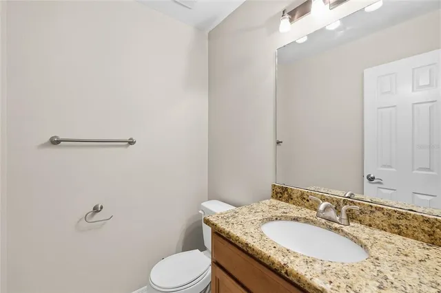 a bathroom with a granite countertop sink toilet and a mirror