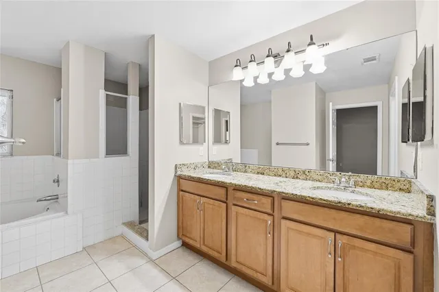 a bathroom with a granite countertop sink a mirror and a bathtub