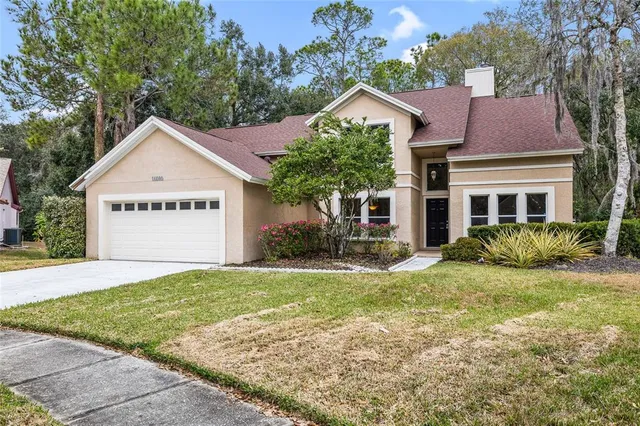 a view of a house with a yard and large tree
