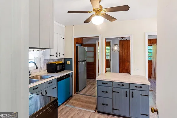 a kitchen with stainless steel appliances granite countertop a refrigerator a sink dishwasher a stove with white cabinets and wooden floor