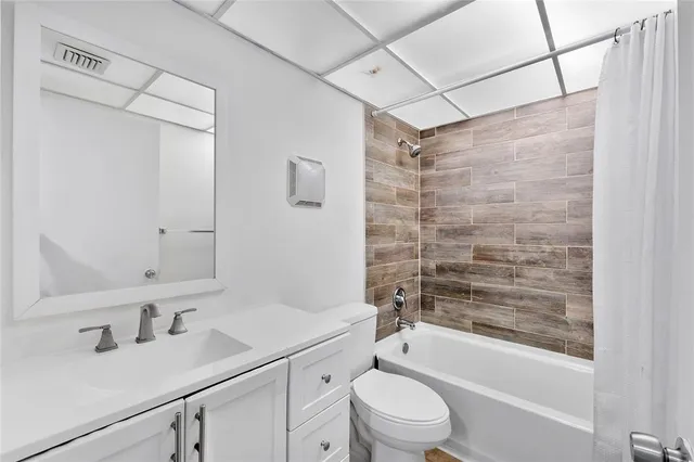 a bathroom with a bathtub shower sink vanity mirror and toilet