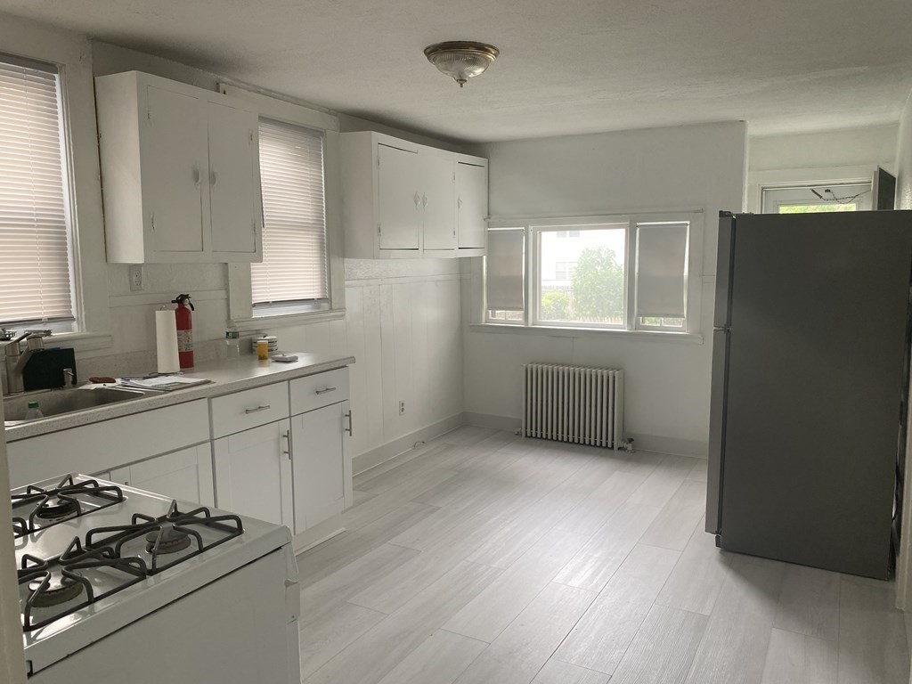 19 Meacham Street, Unit 1 Somerville, MA 02145 - Photo 1 of 11 a kitchen with a window wooden cabinets and a stove