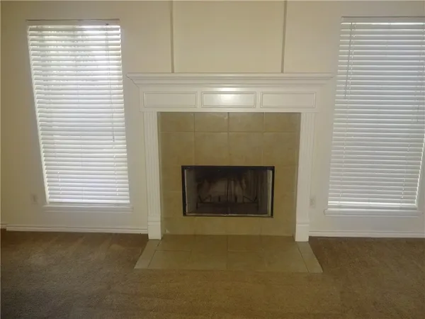 an empty room with windows and fireplace