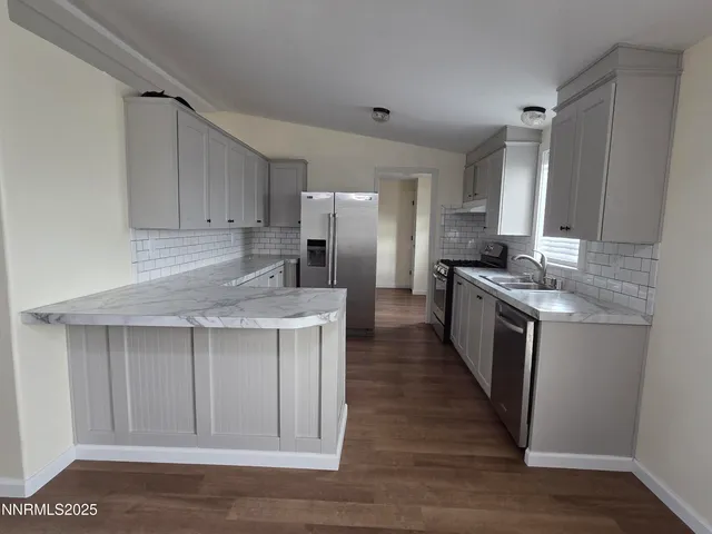 a kitchen with stainless steel appliances granite countertop a stove a sink dishwasher a refrigerator and cabinets with wooden floor