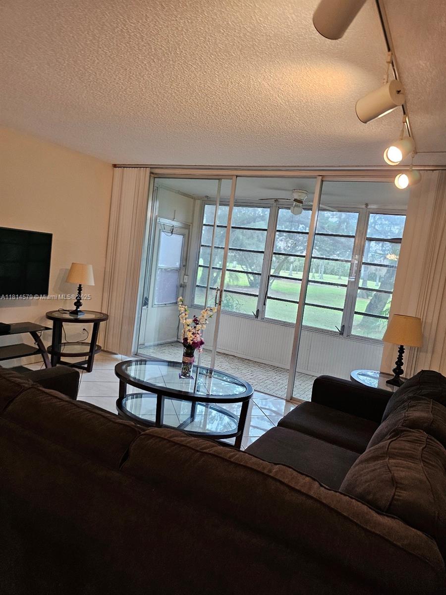 8380 Sands Point Boulevard, Unit J110 Tamarac, FL 33321 - Photo 31 of 34 a living room with furniture and large windows