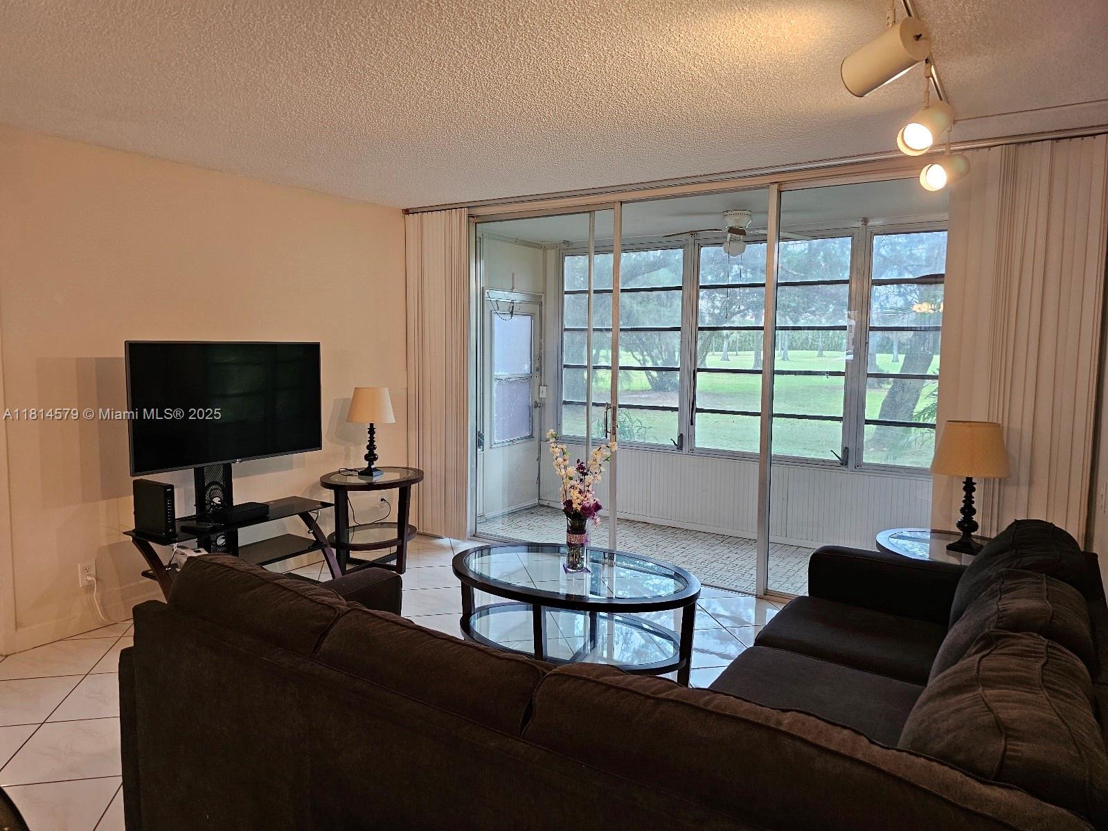 8380 Sands Point Boulevard, Unit J110 Tamarac, FL 33321 - Photo 4 of 34 a living room with furniture and a flat screen tv