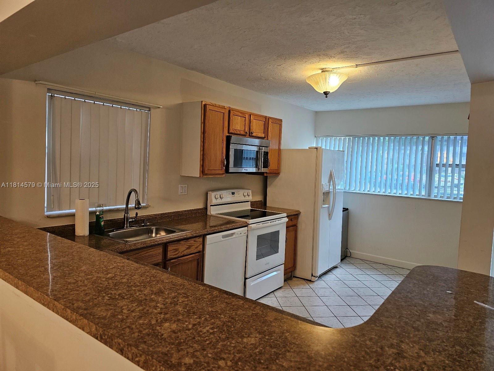 8380 Sands Point Boulevard, Unit J110 Tamarac, FL 33321 - Photo 7 of 34 a kitchen with a sink stove and refrigerator