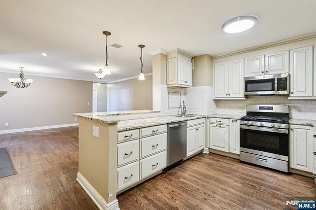 a kitchen with stainless steel appliances granite countertop a sink a stove and a wooden floor