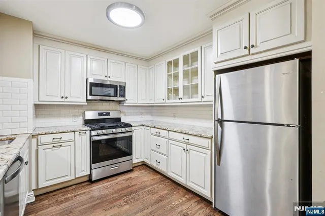 a white kitchen with stainless steel appliances a refrigerator sink and cabinets