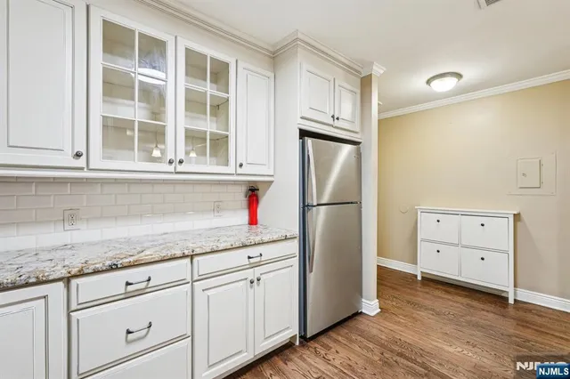 a kitchen with granite countertop white cabinets and refrigerator