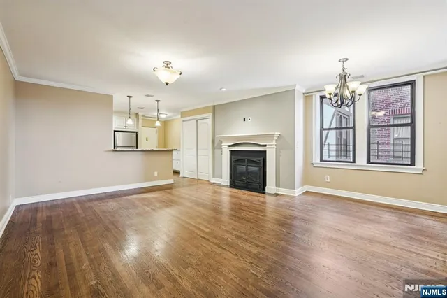 a view of an empty room with window and wooden floor