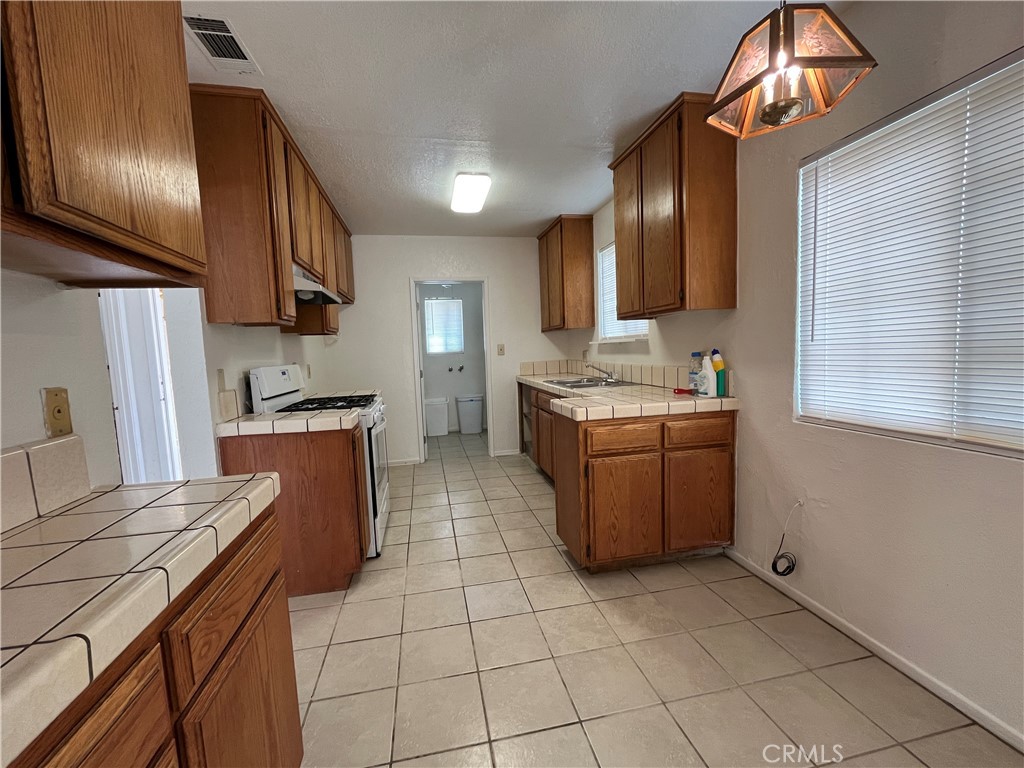 12014 Oasis Road Pinon Hills, CA 92372 - Photo 7 of 16 a kitchen with stainless steel appliances granite countertop a sink counter space cabinets and a stove