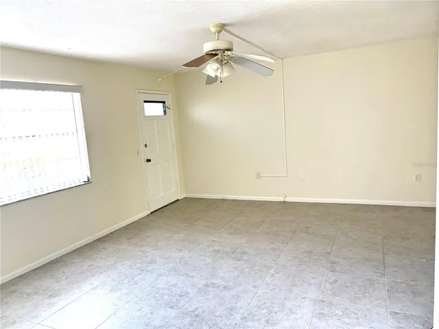 an empty room with a ceiling fan and a window
