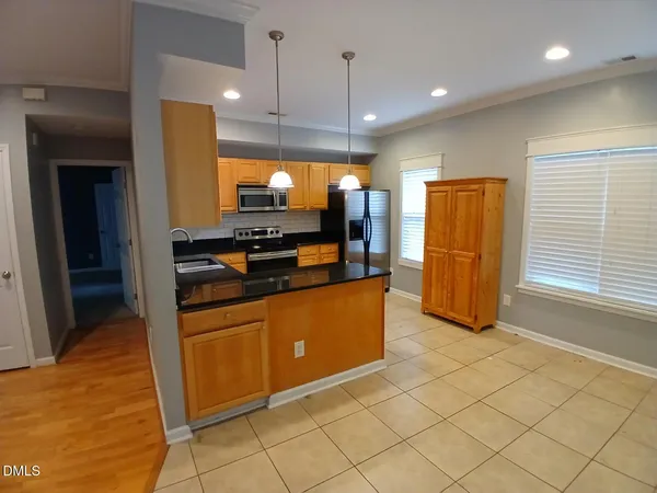 a kitchen with stainless steel appliances kitchen island granite countertop a refrigerator and a stove top oven