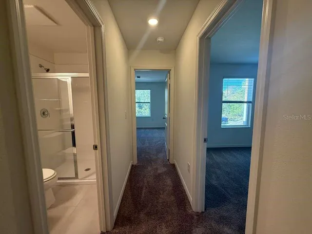 a view of a hallway with wooden floor and a bathroom