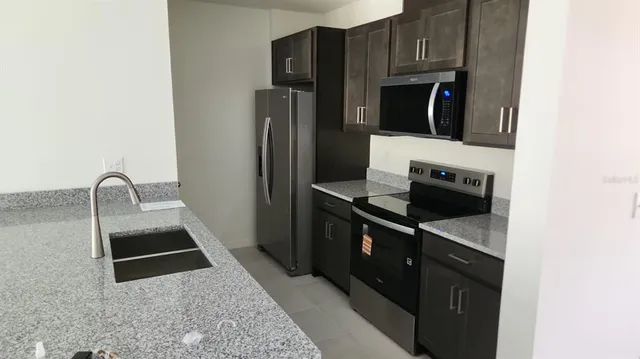 a kitchen with stainless steel appliances granite countertop a refrigerator a stove and a sink