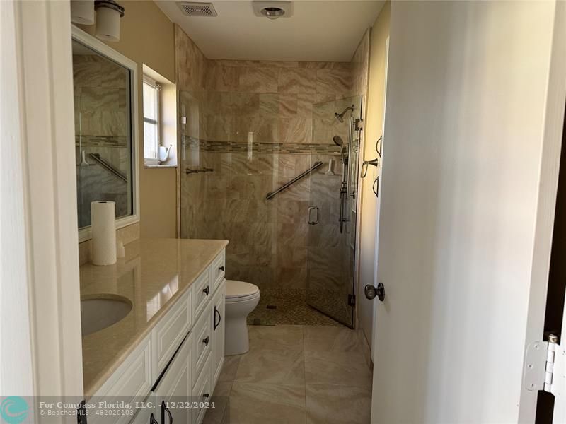 3727 Southwest Whispering Sound Drive Palm City, FL 34990 - Photo 20 of 29 a bathroom with a granite countertop shower a toilet and a sink