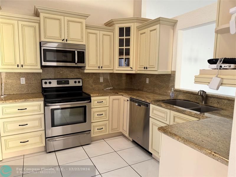 3727 Southwest Whispering Sound Drive Palm City, FL 34990 - Photo 23 of 29 a kitchen with granite countertop a stove top oven microwave and cabinets
