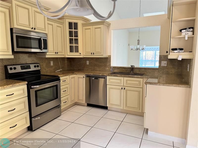 3727 Southwest Whispering Sound Drive Palm City, FL 34990 - Photo 26 of 29 a kitchen with stainless steel appliances granite countertop a stove a sink and a microwave