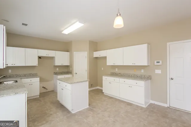 a kitchen that has a sink a stove and a oven with white cabinets