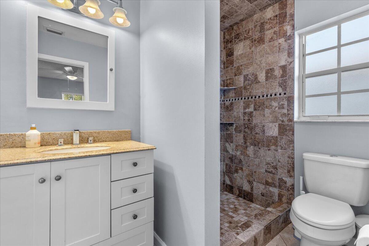 4243 Southwest Utterback Street Port St. Lucie, FL 34953 - Photo 13 of 28 a bathroom with a granite countertop toilet sink and mirror