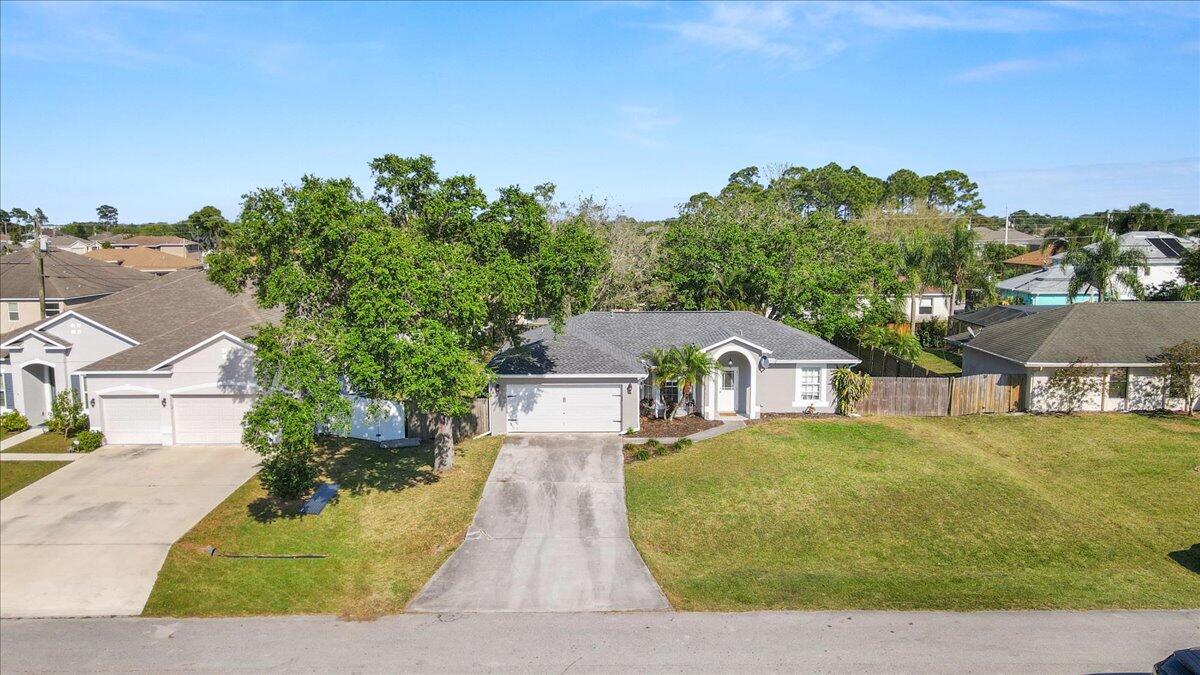 4243 Southwest Utterback Street Port St. Lucie, FL 34953 - Photo 24 of 28 a view of a large house with a big yard plants and large trees