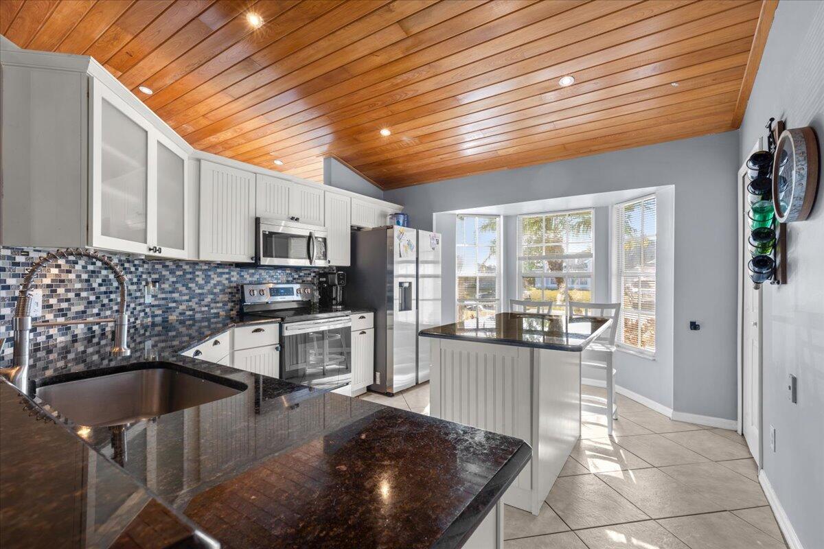 4243 Southwest Utterback Street Port St. Lucie, FL 34953 - Photo 7 of 28 a kitchen with stainless steel appliances granite countertop a sink stove and cabinets