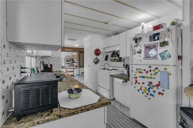 a room with stainless steel appliances kitchen island granite countertop a sink and a refrigerator