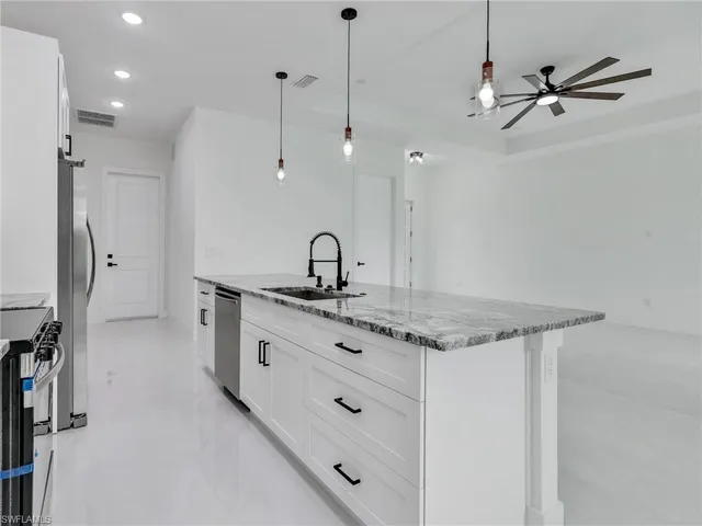 a kitchen with stainless steel appliances granite countertop a sink a stove a refrigerator and island