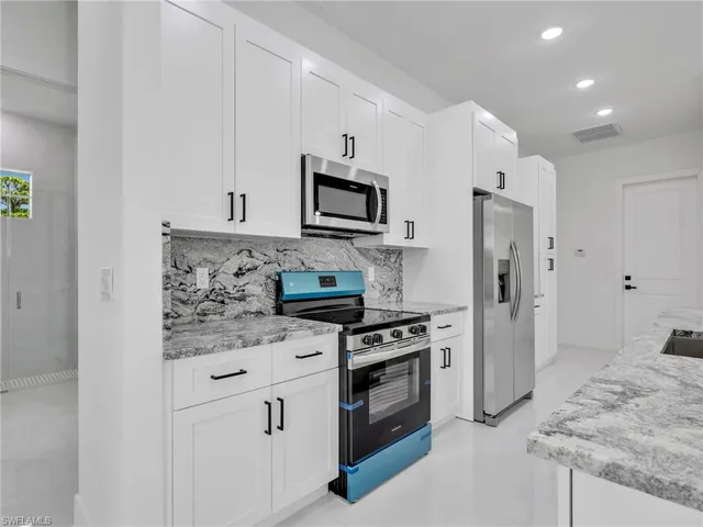 a kitchen with stainless steel appliances granite countertop a stove a refrigerator and a cabinets