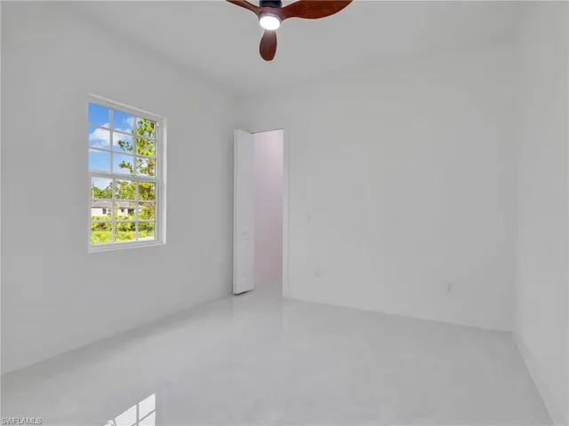 an empty room with a ceiling fan and a window