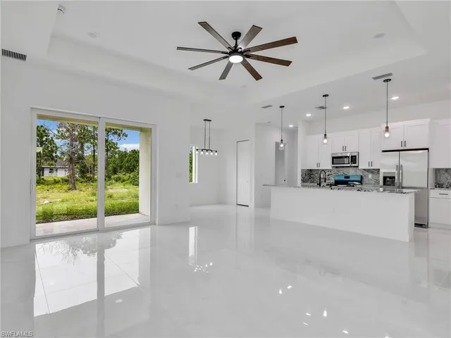 a view of an empty room with kitchen view and a window