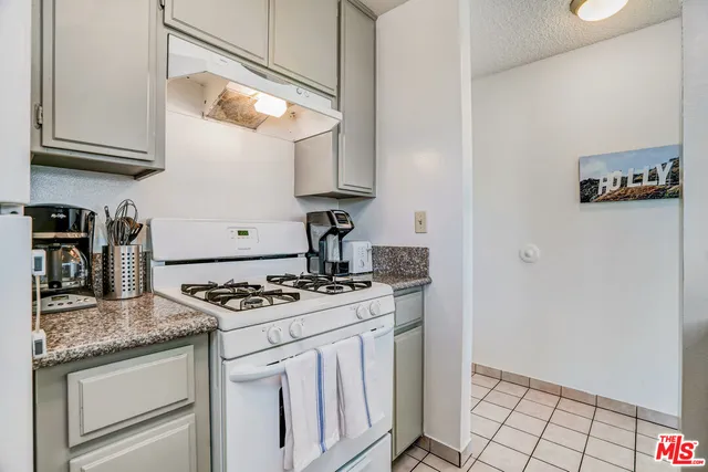 a kitchen with granite countertop a stove and a white cabinets