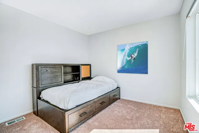 a bedroom with a bed and painting on the wall