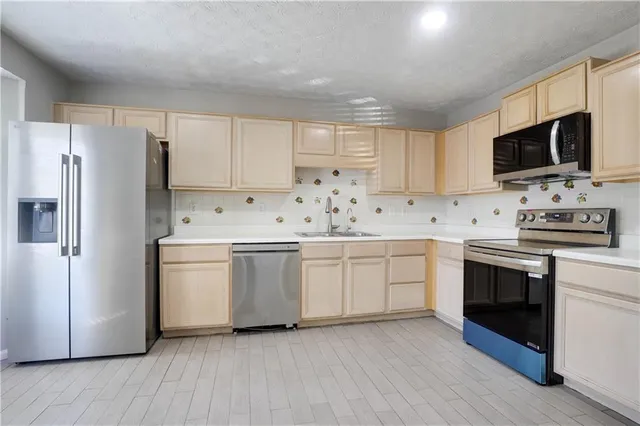 a kitchen with stainless steel appliances a refrigerator stove microwave and sink