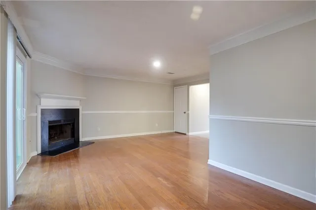 an empty room with wooden floor fireplace and windows
