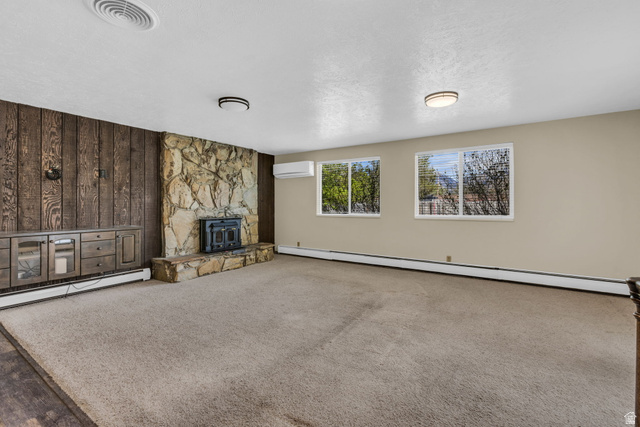 10705 Green Ridge Drive Sandy, UT 84070 - Photo 8 of 55 Unfurnished living room with baseboard heating, wood walls, carpet, and a textured ceiling