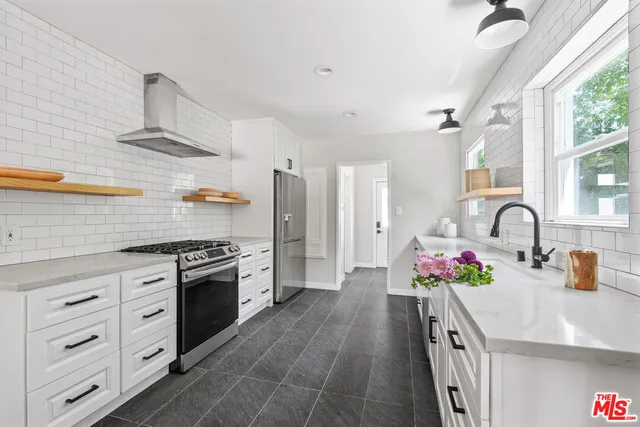 a kitchen with granite countertop a sink stainless steel appliances and cabinets