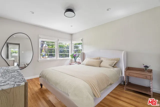 a bedroom with a bed a mirror and a large window