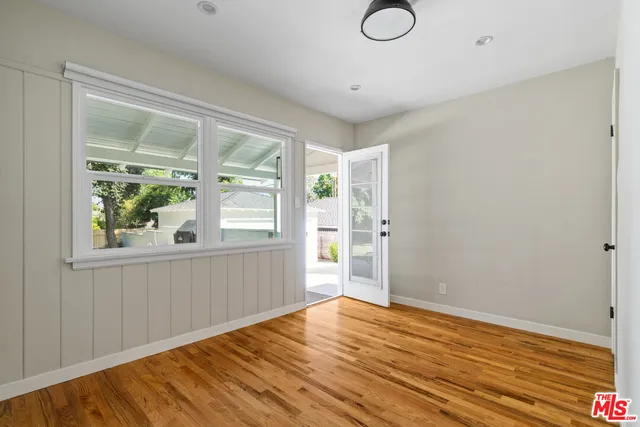 a view of empty room with wooden floor and fan