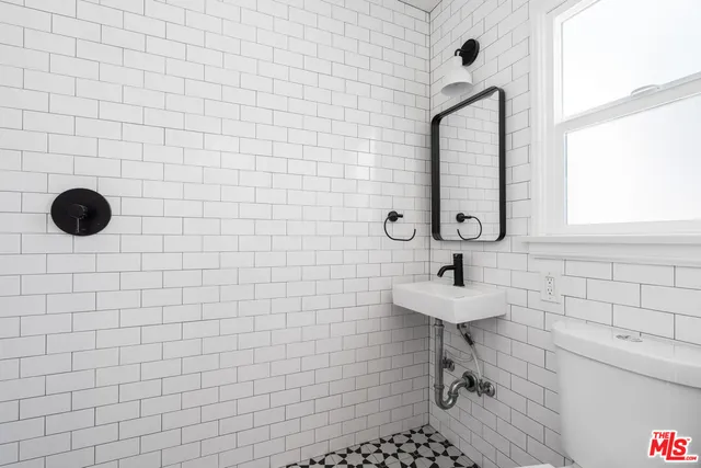 a bathroom with a sink a toilet a mirror and shower