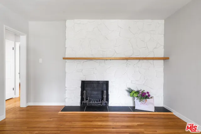 a view of an empty room with wooden floor and a potted plant